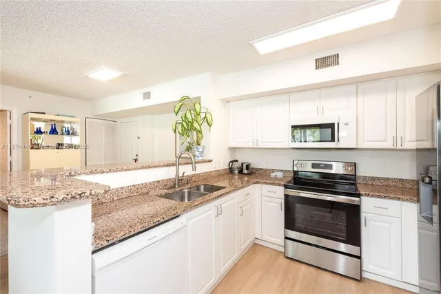 a kitchen with stainless steel appliances granite countertop a sink and cabinets with wooden floors
