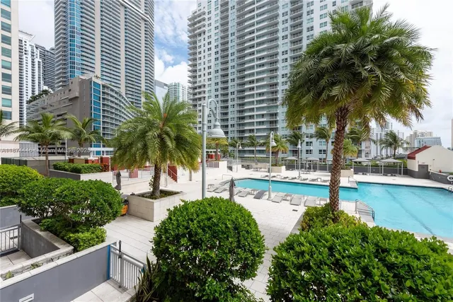 a view of a swimming pool with a lawn chairs and palm tree