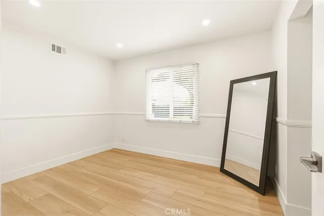 an empty room with wooden floor and mirror