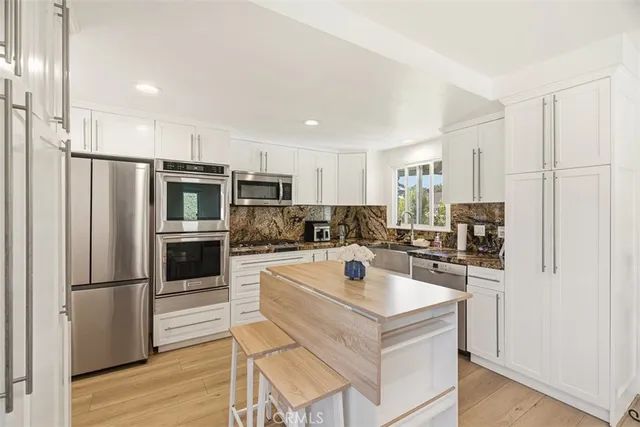 a kitchen with a refrigerator a stove top oven a sink and cabinets