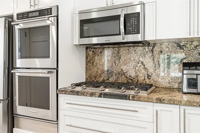 a kitchen with granite countertop white cabinets and stainless steel appliances