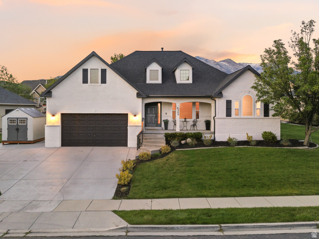 6242 Apollo Way Highland, UT 84003 - Photo 5 of 47 White stucco exterior with dark trim and shutters, featuring an attached two-car garage