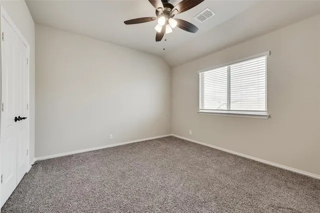 an empty room with a window and a fan