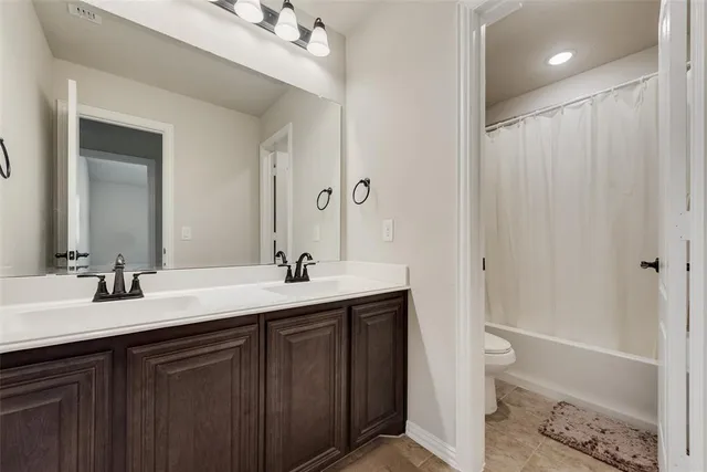 a bathroom with a double vanity sink toilet mirror and bathtub