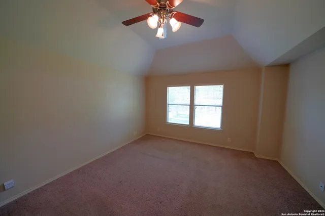 an empty room with a window and a chandelier fan