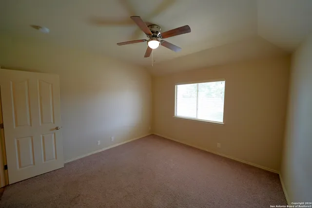 an empty room with a ceiling fan and window