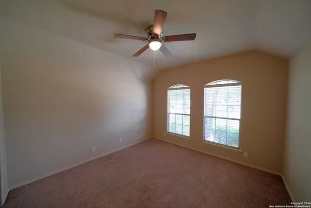 an empty room with chandelier fan and windows
