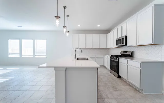 a kitchen with kitchen island granite countertop a sink a stove a microwave and a refrigerator