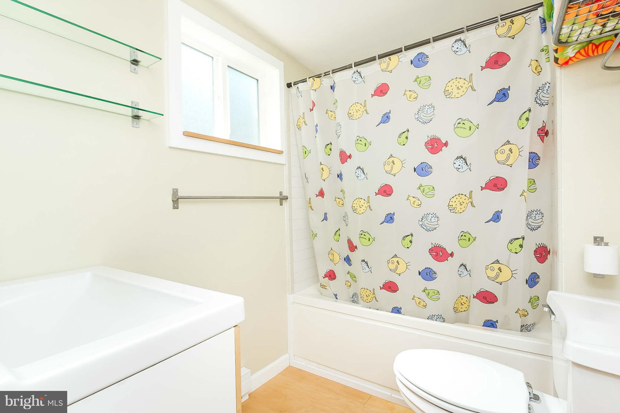 5506 Tramore Road Baltimore, MD 21214 - Photo 23 of 30 a white toilet sitting next to a shower curtain