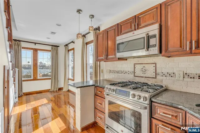 a kitchen with stainless steel appliances granite countertop a stove a sink and a microwave