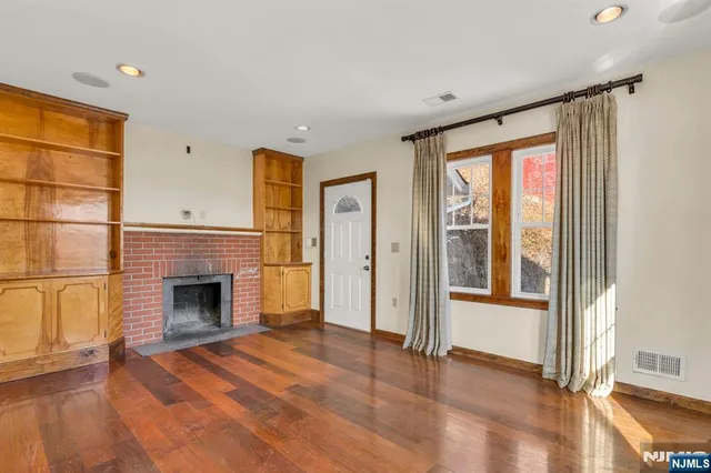 a view of empty room with wooden floor and fireplace