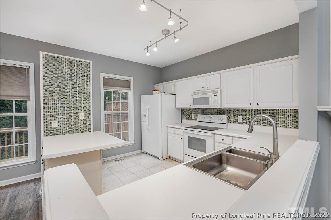5441 Golden Arrow Lane Raleigh, NC 27613 - Photo 11 of 26 a kitchen with stainless steel appliances granite countertop a stove a sink and a refrigerator with white cabinets