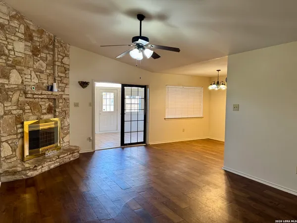 a view of an empty room with wooden floor and a fireplace