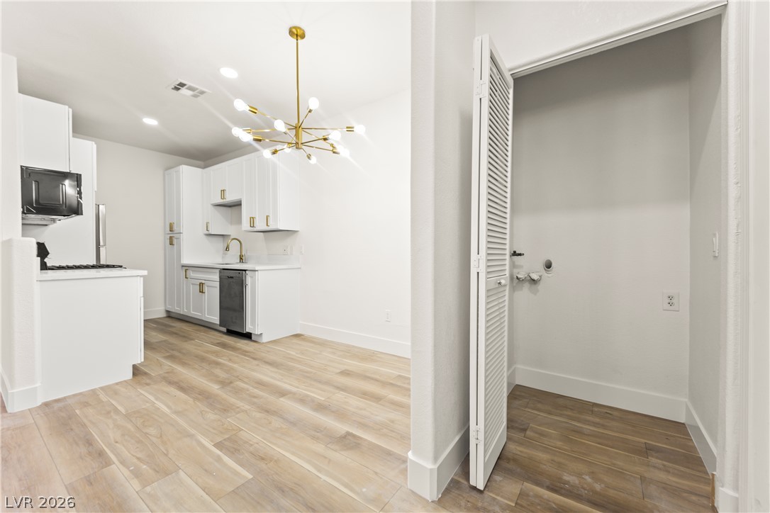 4730 East Craig Road, Unit 1053 Las Vegas, NV 89115 - Photo 12 of 32 A well-appointed kitchen features stainless steel appliances and a stylish overhead light fixture, adjacent to a convenient laundry area.