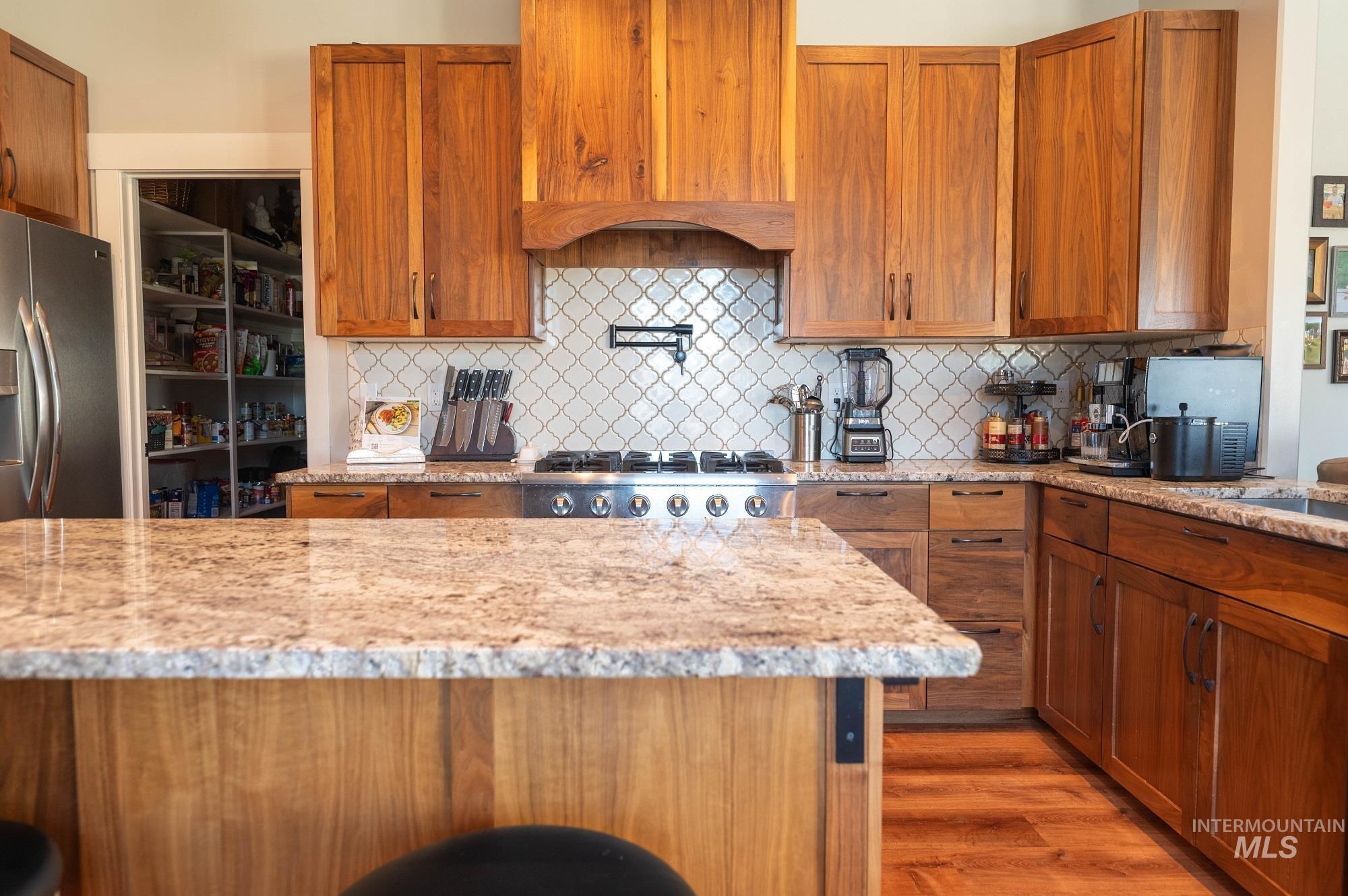 515 School Street Albion, ID 83311 - Photo 7 of 30 Kitchen with brown cabinets, light stone countertops, appliances with stainless steel finishes, and light wood-style floors