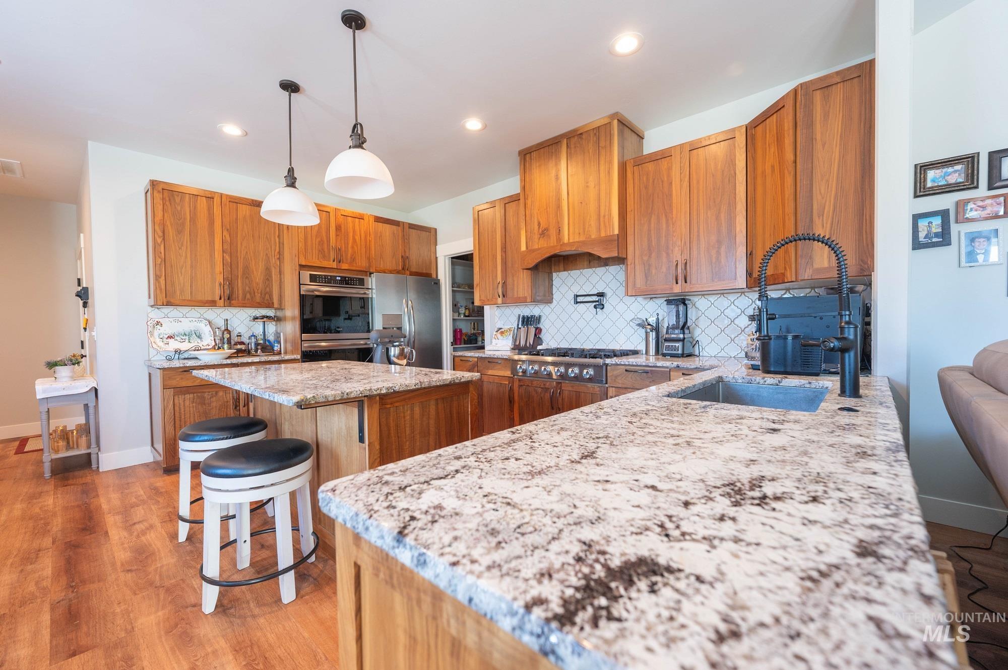 515 School Street Albion, ID 83311 - Photo 8 of 30 Kitchen featuring a kitchen bar, tasteful backsplash, light stone countertops, pendant lighting, and light wood-style flooring