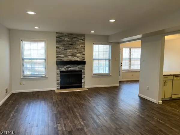an empty room with wooden floor fireplace and windows