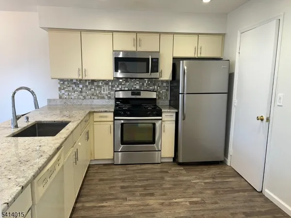 a kitchen with a sink a refrigerator and a stove top oven