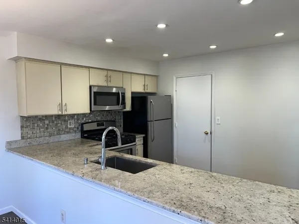 a kitchen with granite countertop a sink and stainless steel appliances