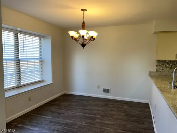 a view of a room with wooden floor chandelier and a window