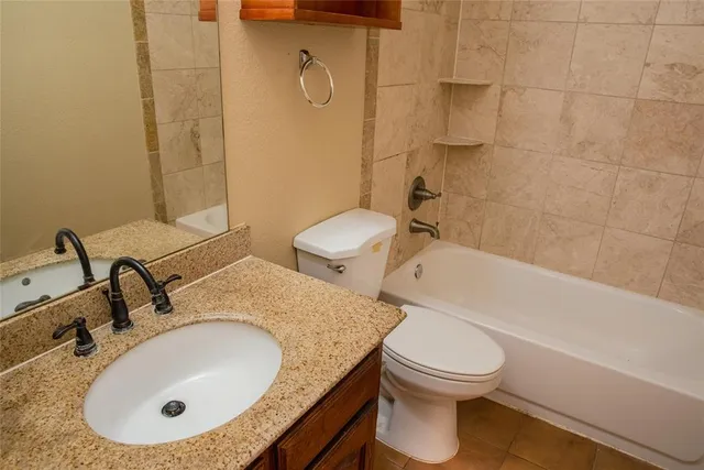 a bathroom with a granite countertop sink a toilet and bathtub