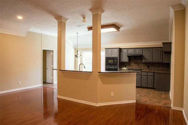 a kitchen with stainless steel appliances granite countertop a refrigerator a stove and a wooden floors