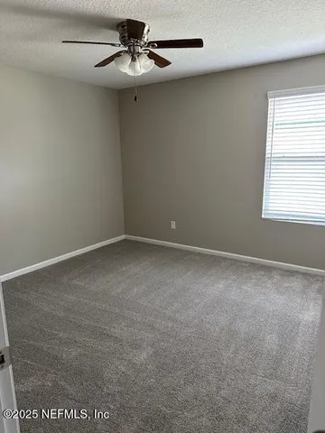 an empty room with a window and a ceiling fan