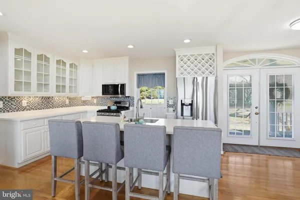 a kitchen with stainless steel appliances granite countertop a stove top oven a refrigerator a dining table and chairs with wooden floor