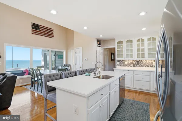 a kitchen with stainless steel appliances kitchen island granite countertop a table chairs sink and cabinets