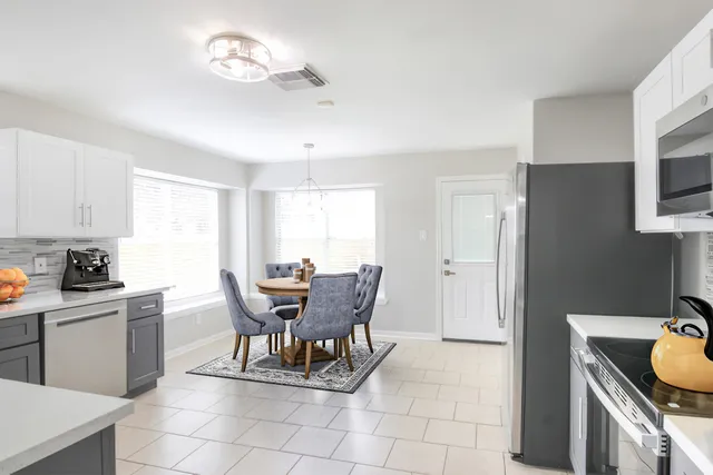 a kitchen with stainless steel appliances granite countertop a stove a refrigerator a sink a dining table and chairs