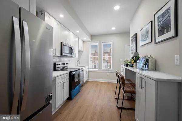 a kitchen with stainless steel appliances granite countertop a refrigerator a stove a sink a dining table and chairs with wooden floor