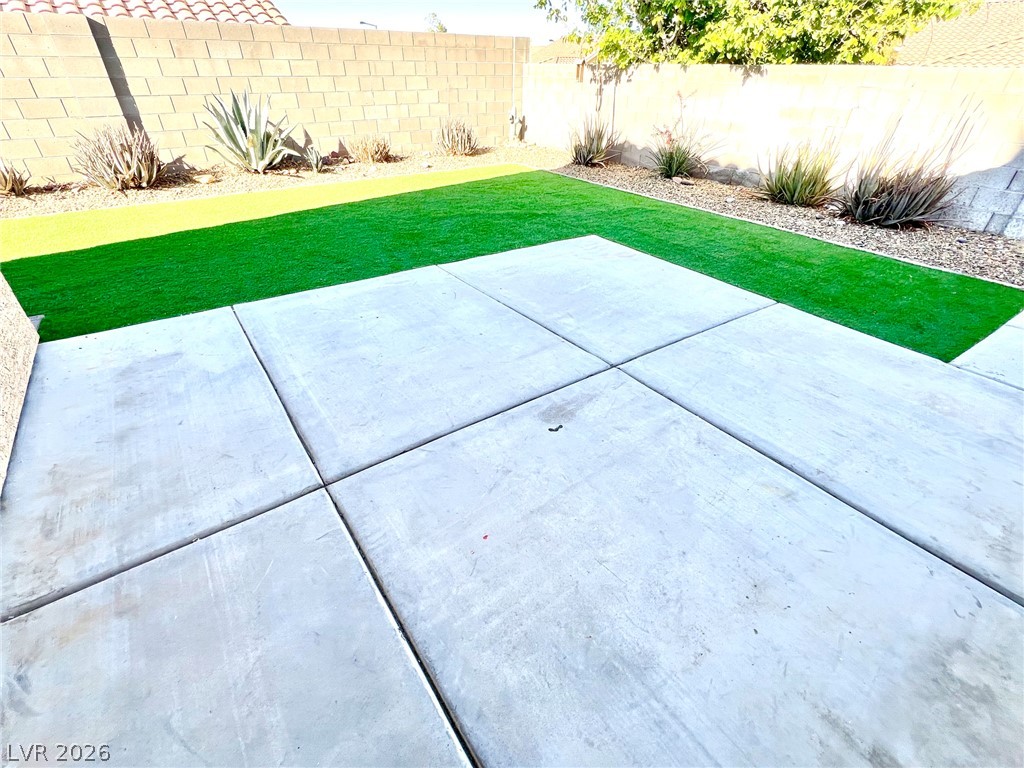 9708 Ridge Creek Place Las Vegas, NV 89134 - Photo 32 of 34 Afternoon shade for relaxing in the backyard. A low-maintenance yard presents a concrete patio and a strip of vibrant green turf for outdoor leisure.