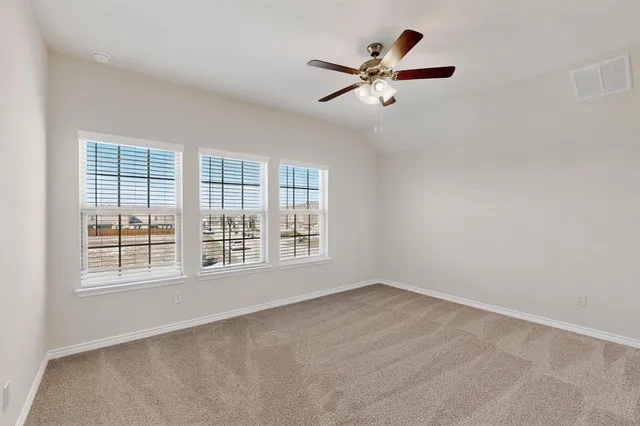 an empty room with wooden floor ceiling fan and windows