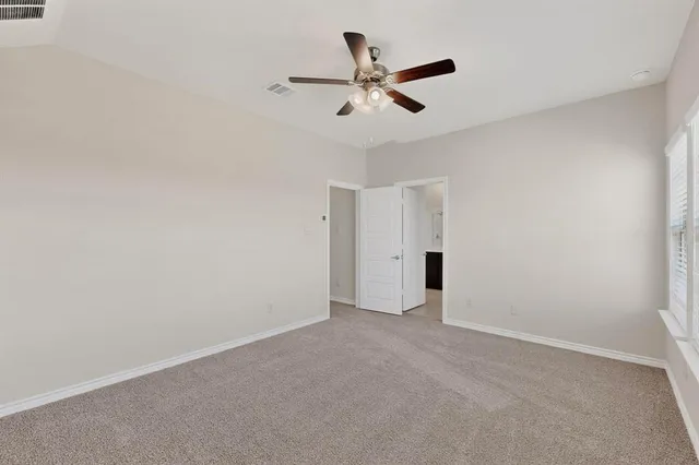 an empty room with chandelier fan and windows