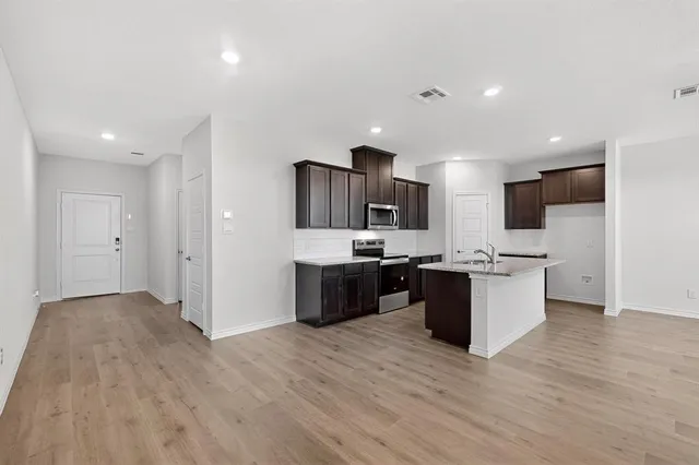 a large kitchen with a large counter top a sink stainless steel appliances and cabinets