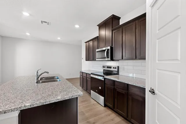a kitchen with granite countertop a sink and steel appliances