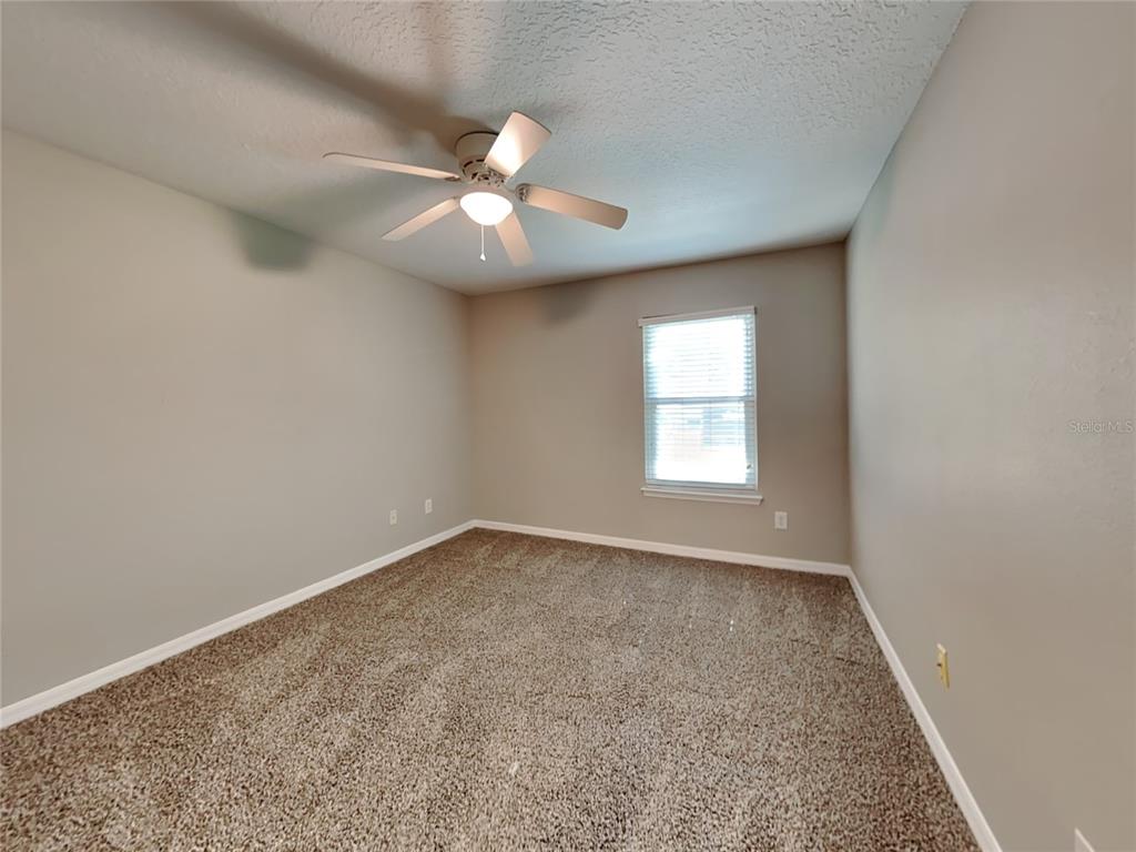 906 Summit Ash Court Deland, FL 32724 - Photo 12 of 19 an empty room with a chandelier fan and windows