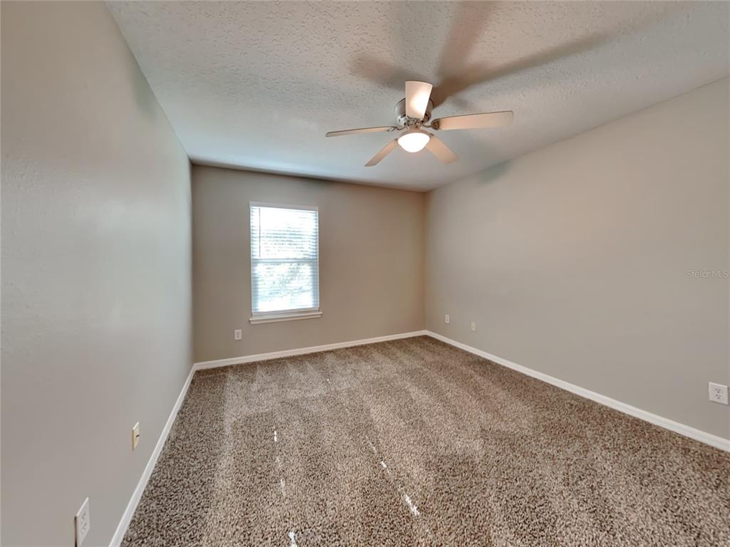 906 Summit Ash Court Deland, FL 32724 - Photo 14 of 19 an empty room with a chandelier fan and windows