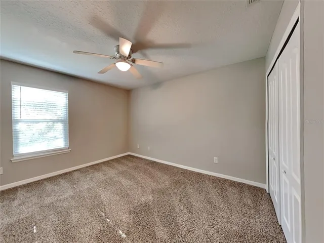 an empty room with windows and fan