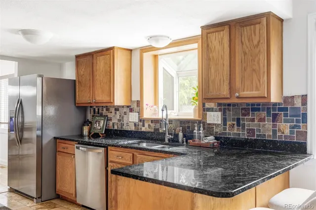 a kitchen with stainless steel appliances granite countertop a sink a refrigerator and a granite counter tops