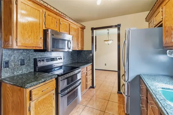 a kitchen with granite countertop a stove a sink and a refrigerator