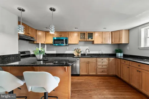 a kitchen with stainless steel appliances granite countertop a sink a stove a dining table and chairs