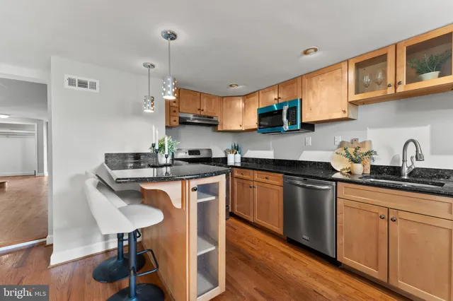 a kitchen with stainless steel appliances granite countertop a sink a stove a microwave a refrigerator and cabinets