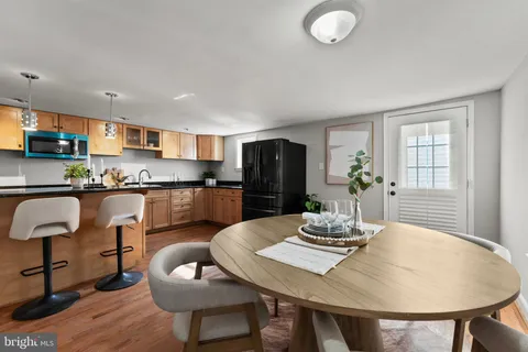 a kitchen with stainless steel appliances granite countertop a dining table chairs and refrigerator