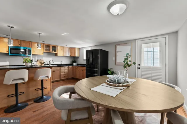 a kitchen with stainless steel appliances granite countertop a dining table chairs and refrigerator
