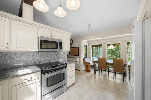 a kitchen with stainless steel appliances granite countertop a stove top oven a sink dishwasher a dining table and chairs with wooden floor