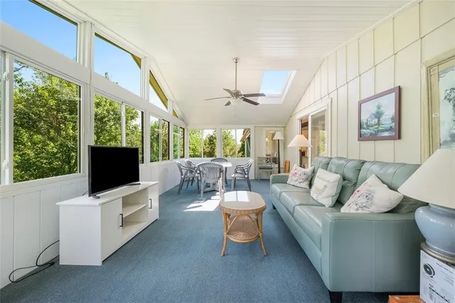 a living room with furniture a flat screen tv and floor to ceiling window