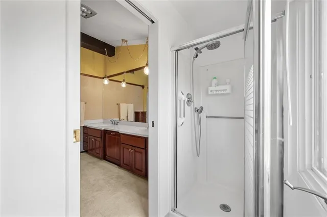 a bathroom with a granite countertop shower sink vanity and mirror