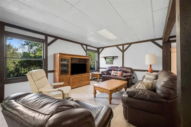 a living room with furniture a flat screen tv and floor to ceiling window