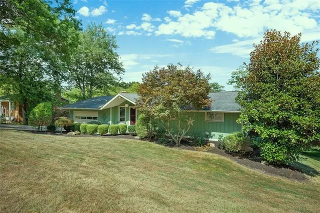 a view of a house with a yard and large trees